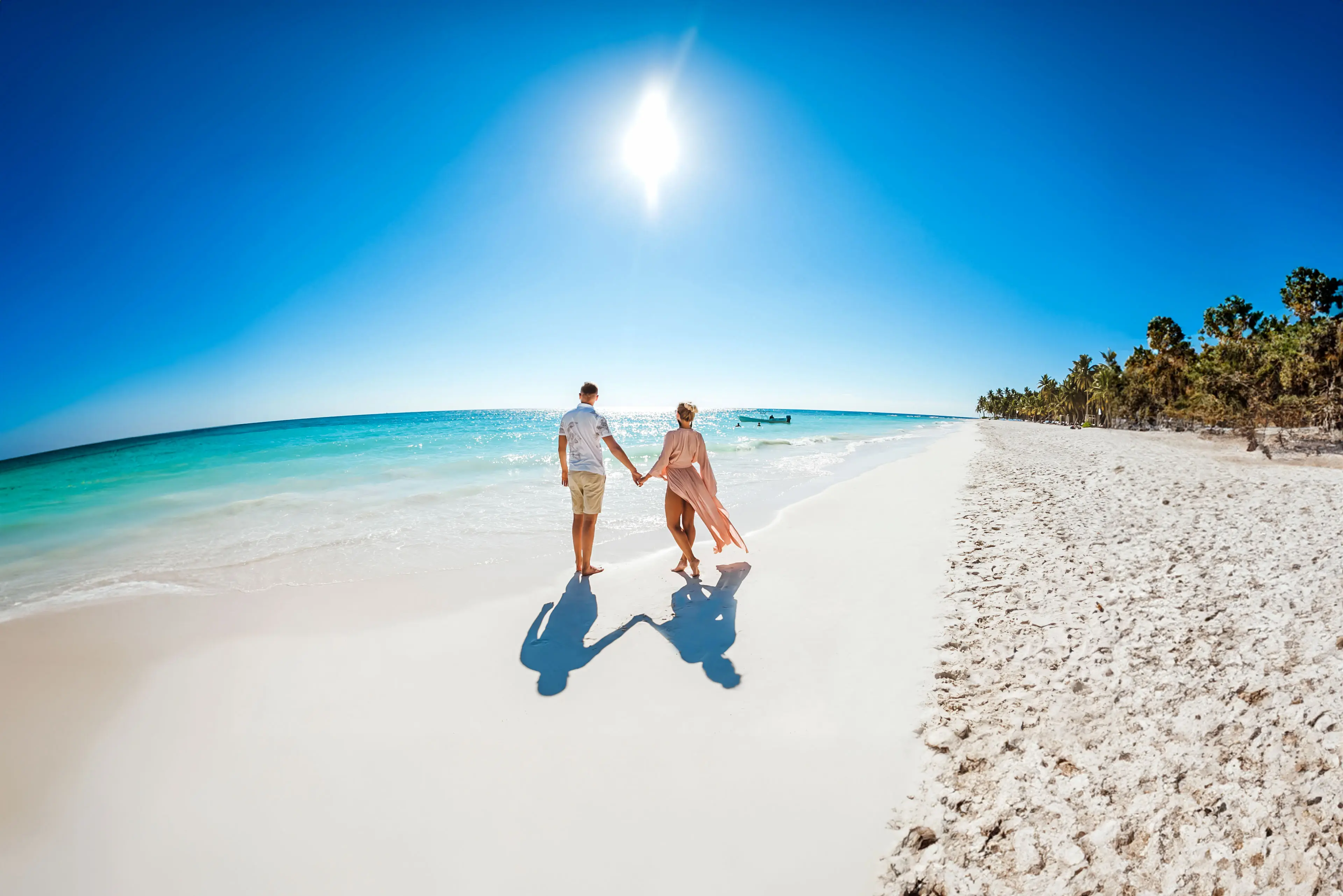 Romantic couple in love hugging, kissing and running on the sandy tropical Caribbean beach in Dominican republic landscape.