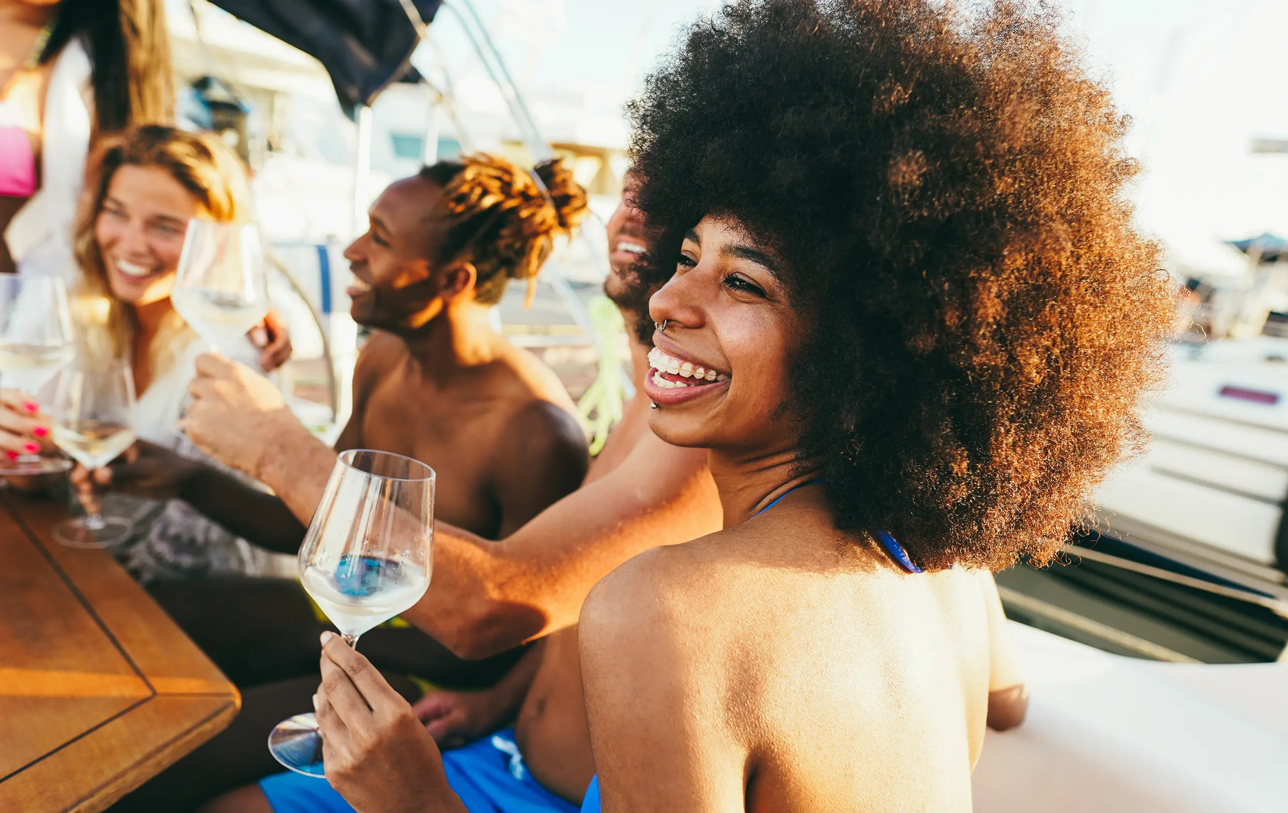 Happy multiracial friends having fun drinking wine at boat party outdoor - Soft focus on african girl face
